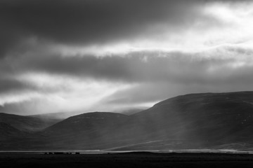 Sunlight penetrates through the clouds and illuminates a rain shower over the Svinadalur at...