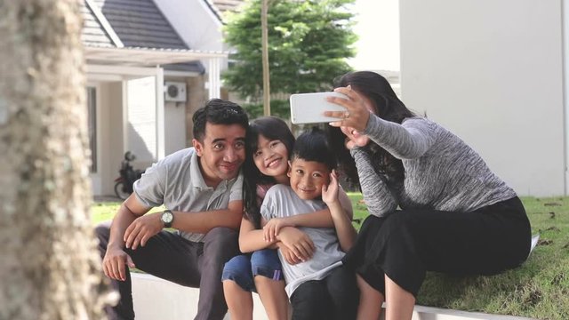 portrait of young happy family taking selfie together. asian father mother and two kids