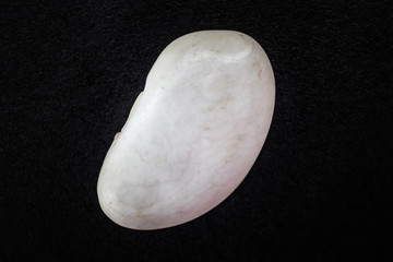 Dried white bean close-up. The concept of healthy food, vegetarianism. Source of protein. Macro photo, black background. Minimalism.