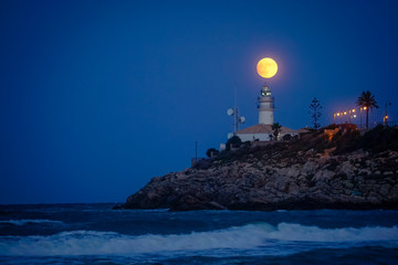 moon eclipse over a lighthouse on the coast