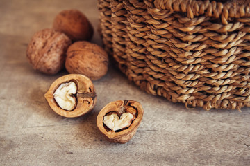 Walnuts in a round wicker basket on a wooden background. Top view. Copy, empty space for text