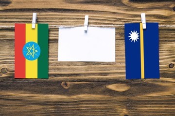 Hanging flags of Ethiopia and Nauru attached to rope with clothes pins with copy space on white...