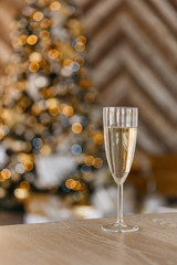 Glass with champagne on background of the New Year tree wit bokeh.