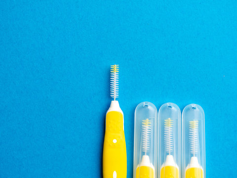 Interdental brush for interdental spaces over blue background with copy space. The concept of good mouth hygiene