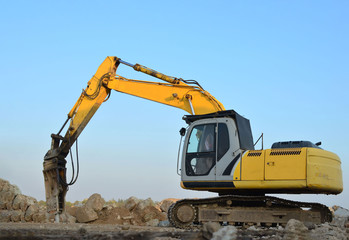 Crawler excavator with hydraulic breaker hammer for the destruction of concrete and hard rock at the construction site or quarry.  Jackhammer using without blasting method. Hard rock demolition