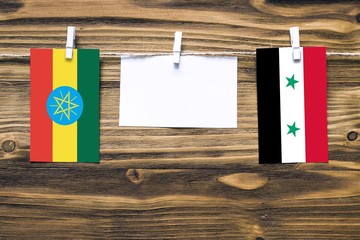 Hanging flags of Ethiopia and Syria attached to rope with clothes pins with copy space on white...