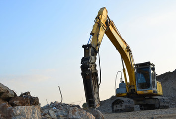 Crawler excavator with hydraulic breaker hammer for the destruction of concrete and hard rock at the construction site or quarry.  Jackhammer using without blasting method. Hard rock demolition