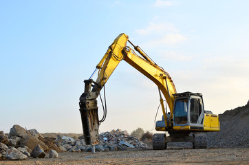 Crawler excavator with hydraulic breaker hammer for the destruction of concrete and hard rock at the construction site or quarry. Roadworks background