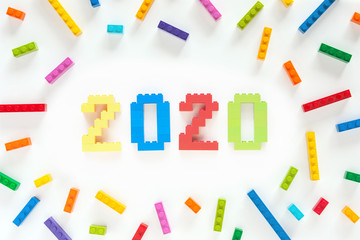 Numbers 2020 made from toys blocks with scattered blocks on white background