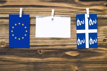 Hanging flags of European Union and Martinique attached to rope with clothes pins with copy space...