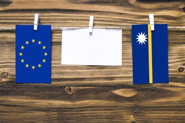 Hanging flags of European Union and Nauru attached to rope with clothes pins with copy space on...