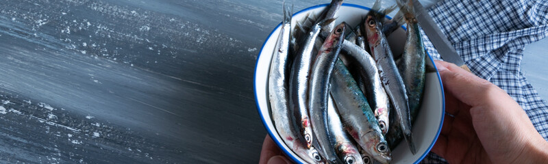 Top view of woman hands preparing fresh anchovies. Healthy raw seafood