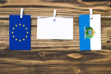 Hanging flags of European Union and San Marino attached to rope with clothes pins with copy space...