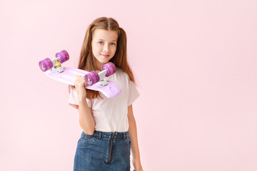 Stylish little girl with skateboard on color background