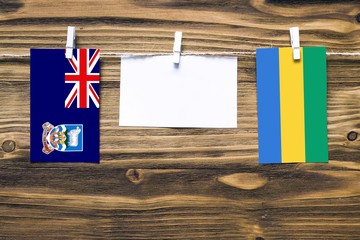 Hanging flags of Falkland Islands and Gabon attached to rope with clothes pins with copy space on...