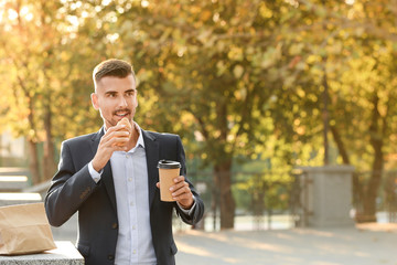 Portrait of handsome businessman having snack outdoors