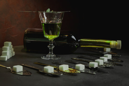 Copa y botella de absenta con algunas cucharitas