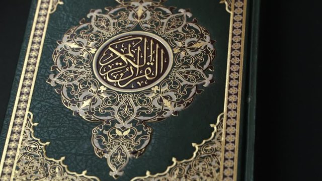the Holy Quran Cover on Book Rest Shift Focus ,  the holy Quran muslim holy book in black background , detail of Quran cover . Muslim lifestyle 