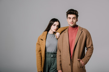 beautiful stylish couple posing in beige coats, isolated on grey