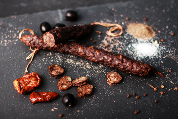 sausage with olives and tomatoes on black background