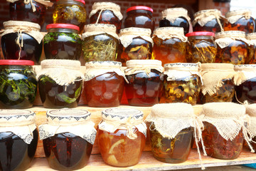 Glass jars with jam and honey standing on shelves at a market. Traditional Harvest Fair