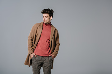 Fototapeta premium fashionable man posing in autumn coat, isolated on grey