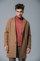 fashionable man posing in trendy beige coat, isolated on grey