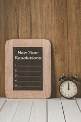 New Year's Resolutions List written on chalkboard with Alarm clock