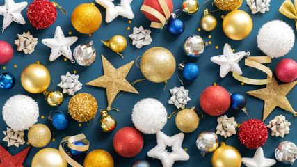 Christmas decorations on blue background. Flat lay composition with stars, balls, ribbon, festive ornaments. Xmas or New Year banner, poster, flyer template.