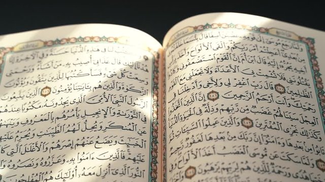 the holy Quran muslim holy book in black background , detail of Quran surah . Muslim lifestyle , arabic calligraphy 