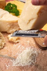 Man cooking with hard italian cheese, grated parmesan or grana padano cheese, hand with grater
