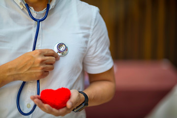 Professional medical doctor with Stethoscope holding a red heart. Concept of health care.
