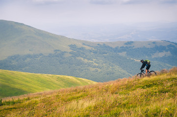 Fototapeta na wymiar Beautiful mountain landscape with clouds. Tourist on a bicycle in the Carpathian mountains descends from the top of the Gimba.