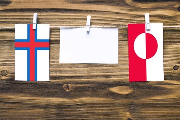 Hanging flags of Faroe Islands and Greenland attached to rope with clothes pins with copy space on...