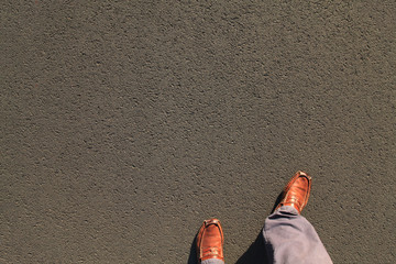 Feet in shoes (loafers or moccasins) on asphalt surface. Detailed texture background of the bitumen...
