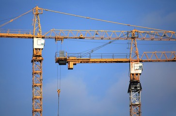 Altitudinal construction cranes on the blue sky background. Building construction site with cranes. The construction of modern apartment buildings