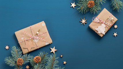 Christmas holiday composition with vintage gift boxes wrapped craft paper, fir tree branches, wooden handmade decorations over dark blue background. Flat lay, top view, copy space. Xmas banner mockup