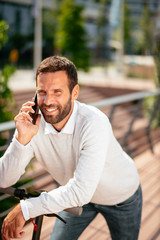 Young businessman outdoors. Young businessman outdoors. Handsome businessman driving electric scooter while using phone.