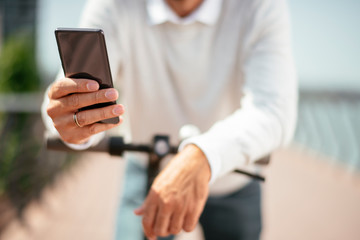 Close up of man holding phone while riding electric scooter