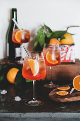 Aperol Spritz aperitif alcohol cold drink in glasses with straws with oranges and ice cubes on...