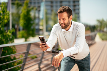 Young businessman outdoors. Young businessman outdoors. Handsome businessman driving electric scooter while using phone. © JustLife