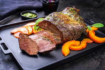 Traditional roasted beef heart with fried pumpkin slices and chimichurri sauce as closeup on a...