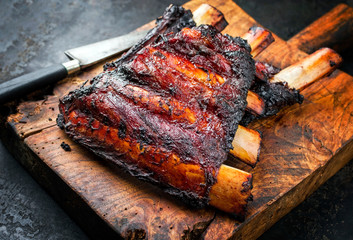 Barbecue burnt chuck beef ribs marinated with hot chili sauce as closeup on an old rustic wooden...