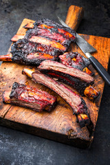 Barbecue burnt chuck beef ribs marinated with hot chili sauce sliced as closeup on an old rustic wooden cutting board