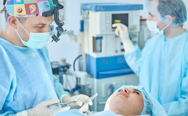 Several doctors surrounding patient on operation table during their work. Team surgeons at work in operating room