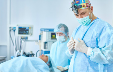 Several doctors surrounding patient on operation table during their work. Team surgeons at work in...