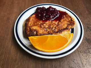 French toast with orange and red berries on white plate, top view.