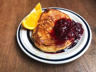 French toast with orange and red berries jam on white plate