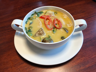 Delicious and tasty Thai chicken green curry, creamy soup, with eggplant and sweet basil. Decorated with sliced chili. Serve in white bowl.