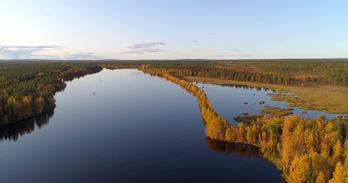 River in Lapland,  Aerial, tracking, drone shot, panning around a esker on the Almansuvanto stream, surrounded by foliage color forest at golden hour, on a sunny, fall evening, in Sodankyla, Finland